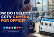 A modern office with a visible CCTV camera mounted on the ceiling, overlooking desks and workstations.