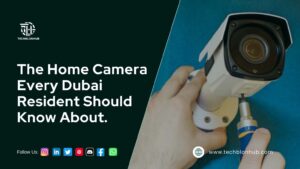 The image features a home security camera installation, showcasing a person using a screwdriver to install a white security camera against a blue background. On the left, bold white text states, "The Best Security Camera Every Dubai Resident Should Know About." Social media icons for platforms like Instagram, LinkedIn, Twitter, YouTube, WhatsApp, and Facebook are displayed at the bottom, along with the website www.techblonhub.com. The Techblon Hub logo is positioned in the top left corner.